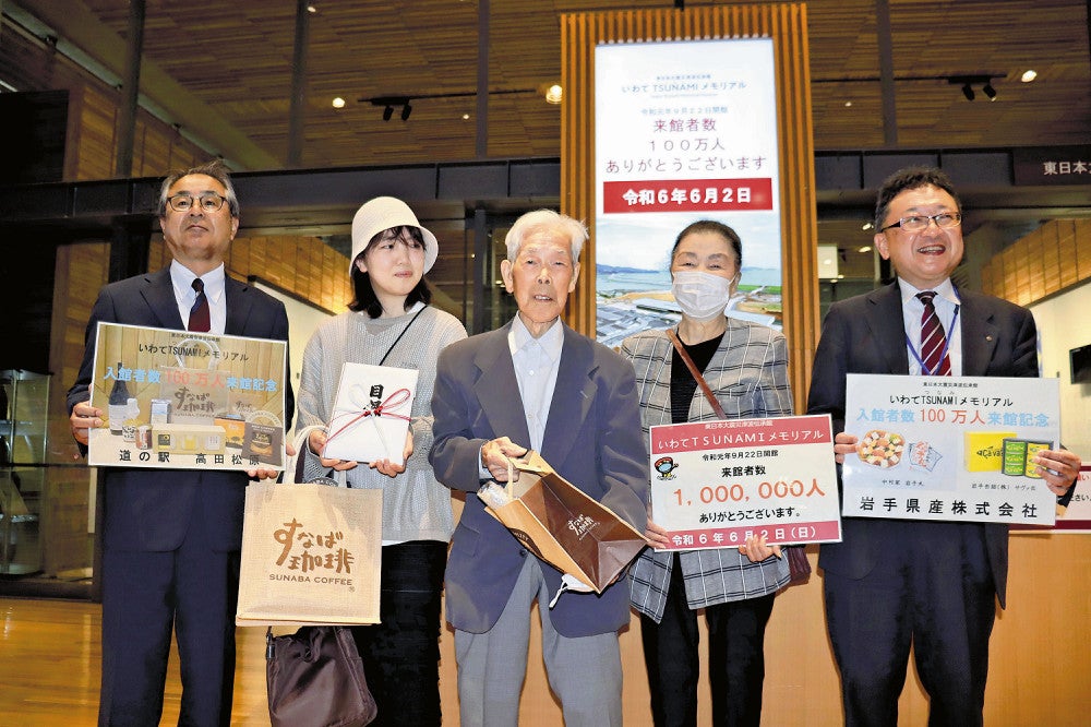 １００万人目の来館者となった男性（中央）（２日、陸前高田市で）
