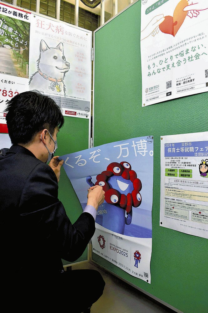 掲示板から万博のポスターをはがす市職員（大阪府交野市役所で）