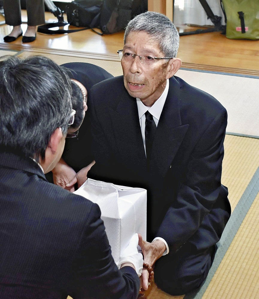 県の担当者から遺骨を受け取る正紘さん（右）