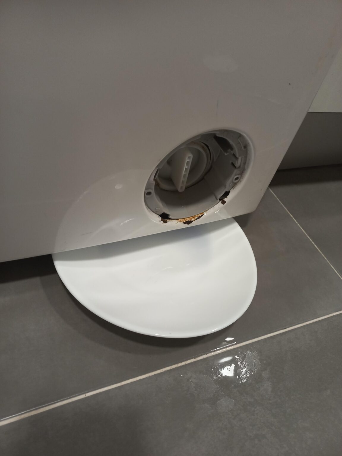 洗濯機のフィルターの下から水が滴る