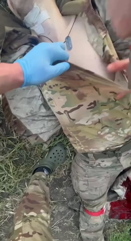負傷したロシア兵がすでに失血して地面に横たわり、同志が服を切り裂いて肩の部分に何かを注射した