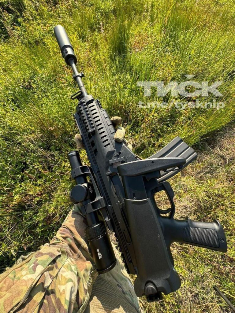 ウクライナ軍兵士がスコープとサプレッサーを付けたイタリア製ベレッタ ARX 160 アサルトライフルの写真を撮る。