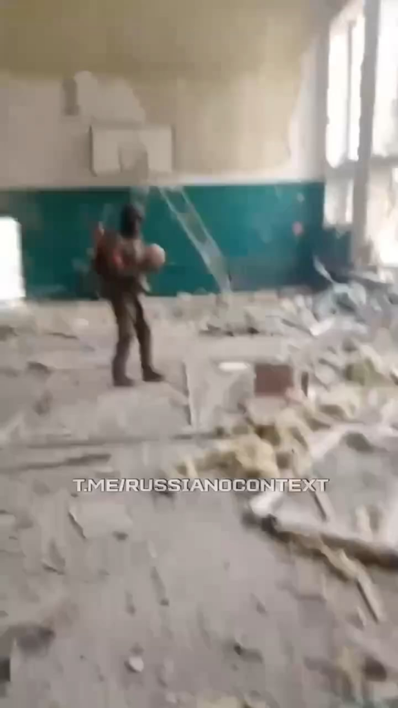 破壊された体育館でバスケットボールをするロシア兵、その隣には遺体袋に入った戦友の死体が横たわる - 日付と場所は不明