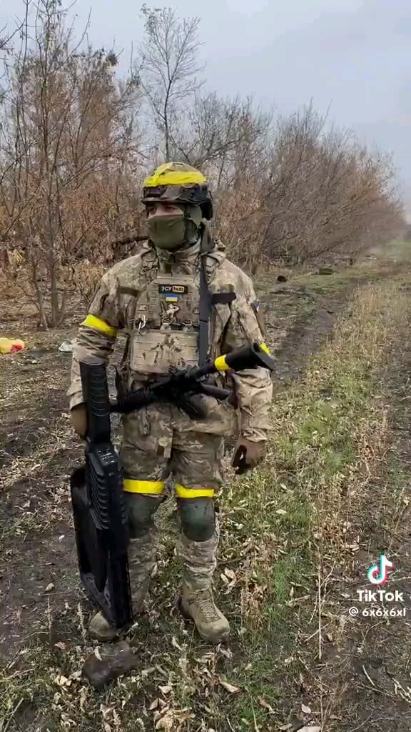 背景で何かが爆発する中、ウクライナの兵士が対ドローン銃を差し出す。