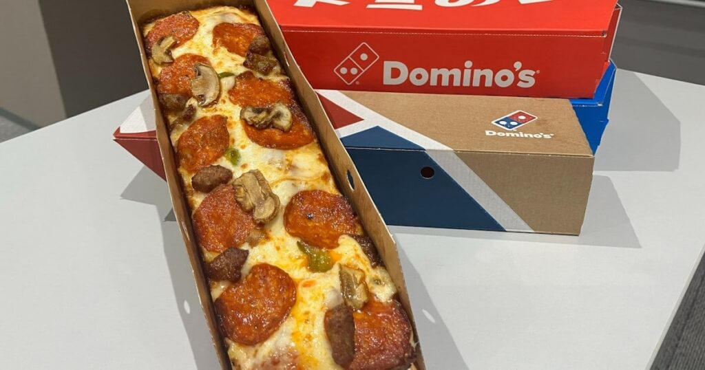 ドミノ・ピザ、片手で食べやすい長方形ピザ 一人客に的