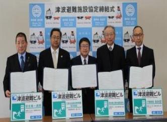 5名の関係者の人たちが一人一人協定書を持ち記念撮影をしている写真