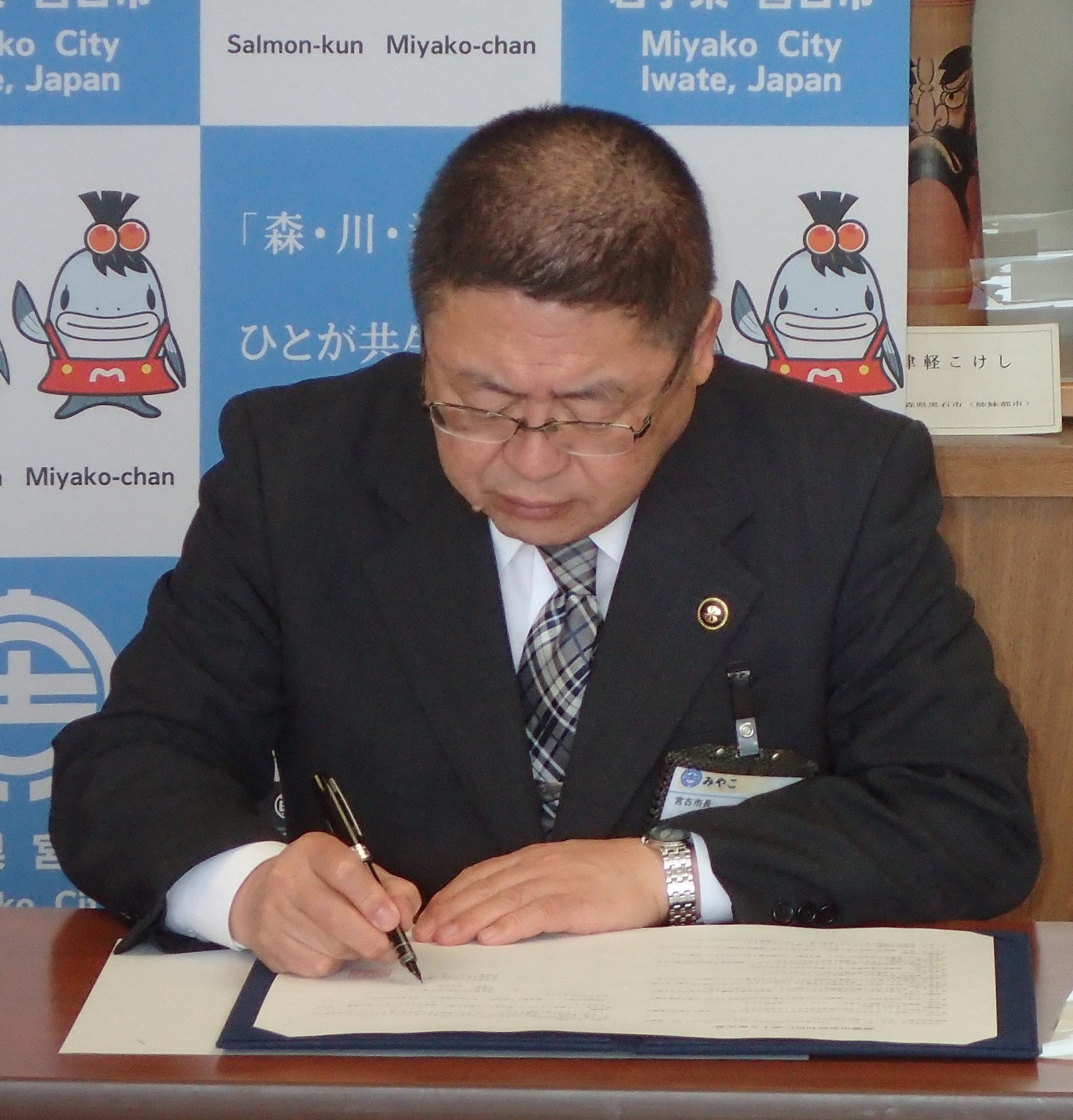 山本正徳 宮古市長が協定書にサインをしている写真
