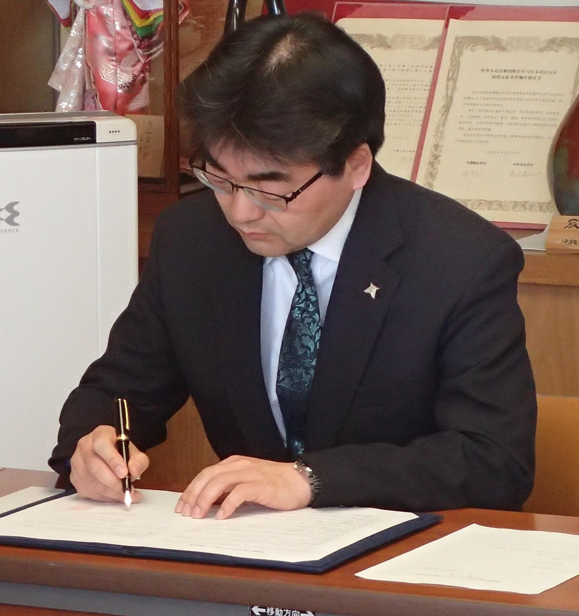 熊谷和浩校長が協定書にサインをしている写真