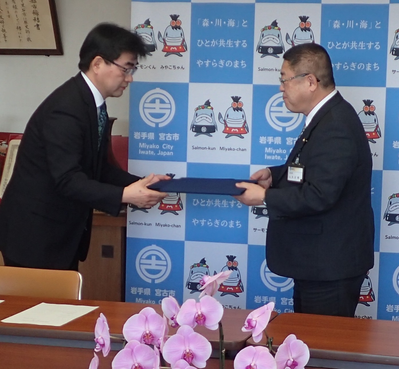 熊谷和浩校長と山本正徳 宮古市長が向かい合わせに立ち協定書の受け渡しをしている写真