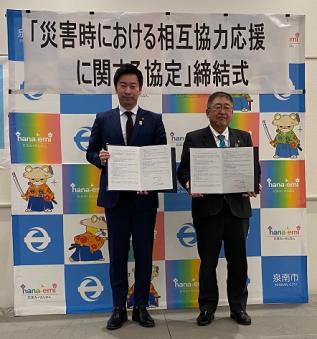 山本優真市長と山本市長が協定書を持ち2人で並んで記念撮影をしている写真