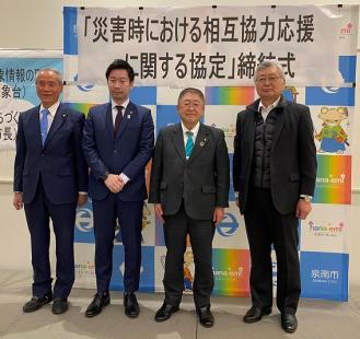 「災害時における相互協力応援に関する協定」の締結式で関係者4名が並んで記念撮影をしている写真