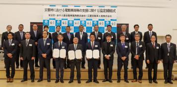 1列目中央の3名が締結書を持ち2列に並んだ23名の関係者の人たちが記念撮影をしている写真