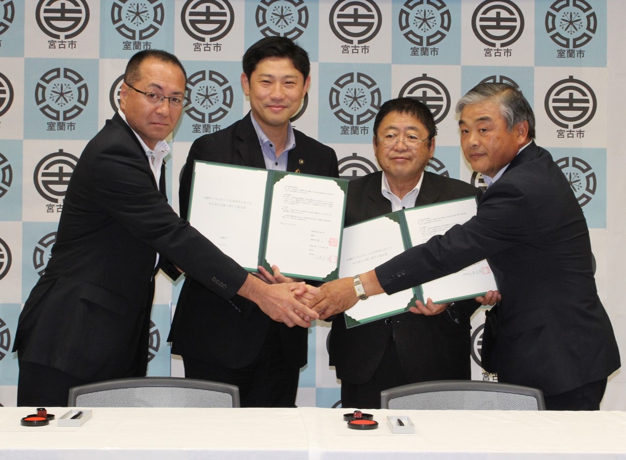 4名の関係者の人たちが「災害時等における相互協力応援に関する協定」の締結式で手を合わせ記念撮影をしている写真