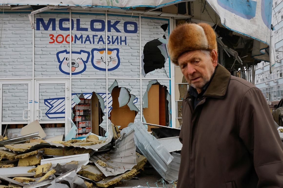 ロシア占領下のドネツクで砲撃によって破損した建物の横を歩く住民＝１月/Alexander Ermochenko/Reuters