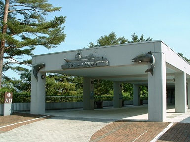 岩田県立水産科学館建物入口に上部中央に船、左右にイルカのような魚のオブジェが施された外観の写真