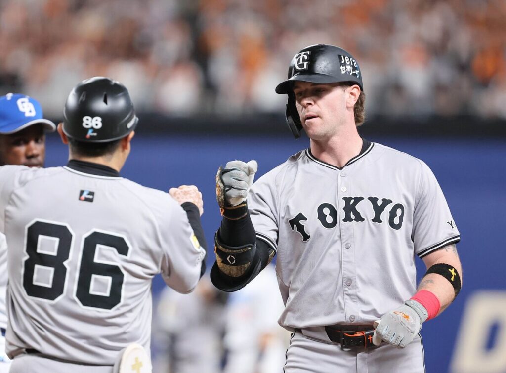 ５回無死一塁、トレイ・キャベッジが左前打を放ち、一塁上で古城茂幸内野守備走塁コーチ（左）とグータッチを交わす　（カメラ・馬場　秀則）