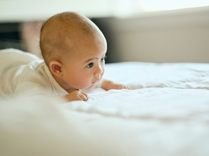 ベッドの上で前を見つめている赤ちゃん