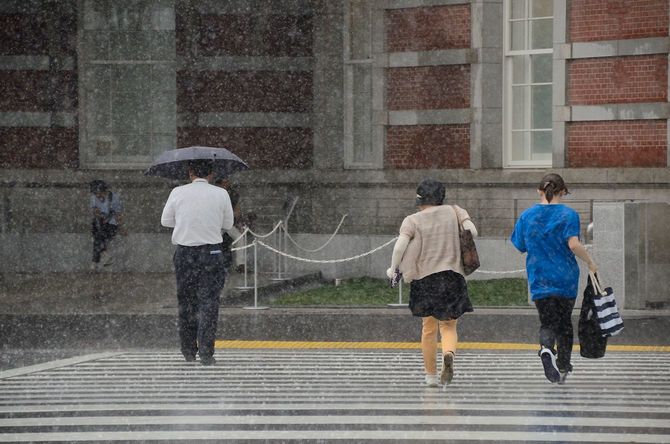 大雨の中、東京駅に向かって走る人々