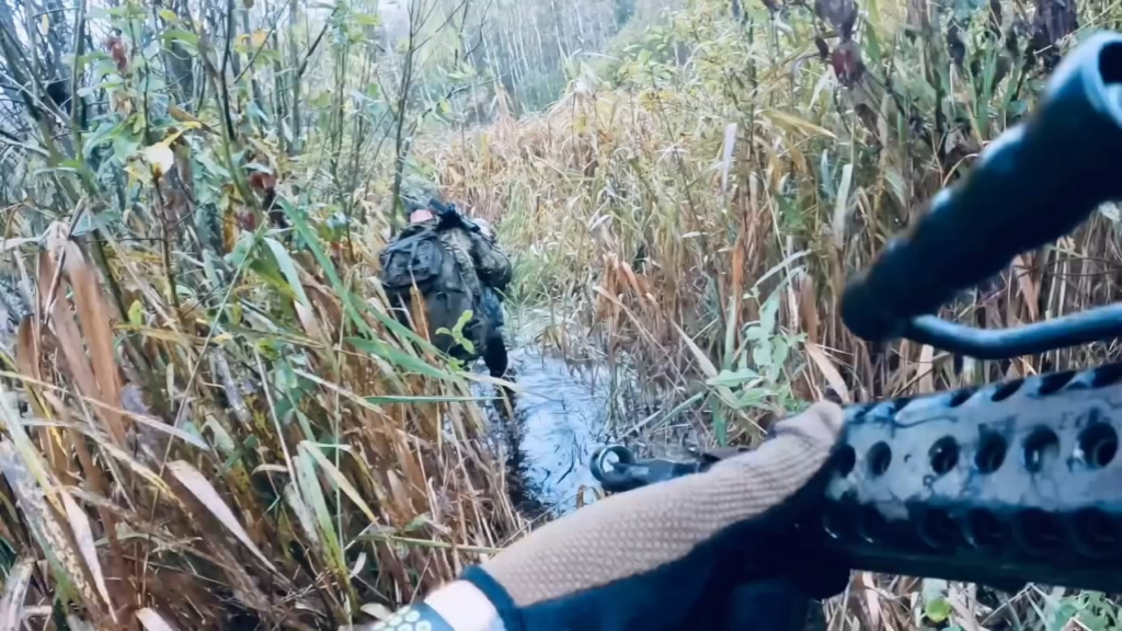ウクライナの特殊部隊は、敵の領土への襲撃中に湿地の地形を移動します。おそらくベルゴロド地域、2024年のビデオ。