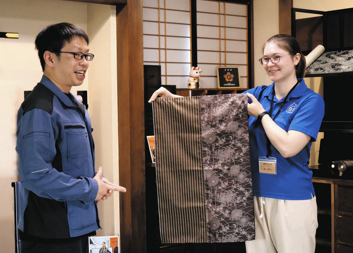 展示される牛首紬を手にするメイ・スーザンさん（右）と西山幹人さん＝白山市の「牛首紬×ＭＩＺＥＮ白山店＜加賀乃織座＞」で
