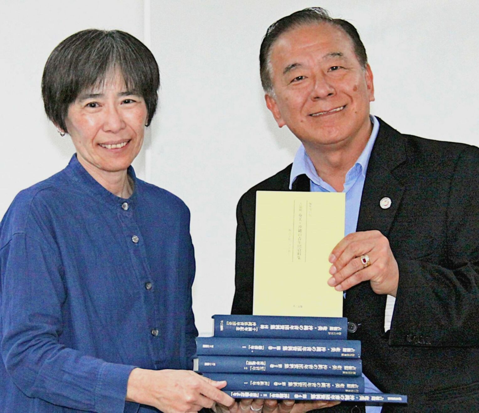 ブラジル沖縄県人会の知花ルイ会長（右）に資料集を手渡す熊本大学の山城千秋教授＝ブラジル・サンパウロ市