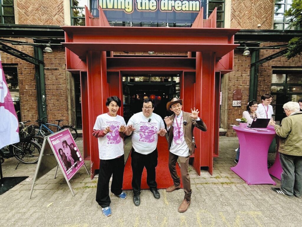 映画祭の会場で怪獣ポーズを決める（右から）八木監督、お笑いコンビ・春とヒコーキのぐんぴぃさん、土岡哲朗さん＝ドイツ・フランクフルトで