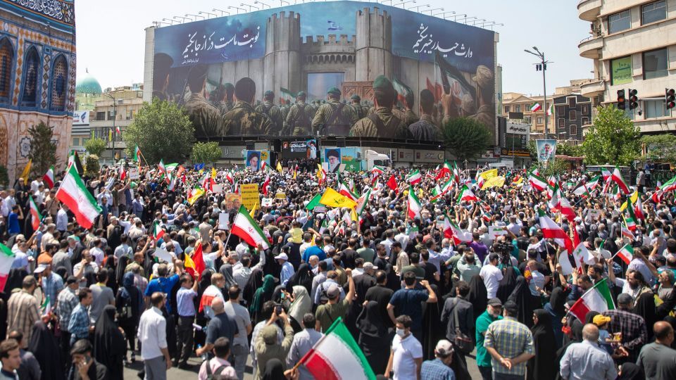 テヘラン中心部でイラン国旗などを振り、イスラエルの攻撃に抗議するデモ参加者ら/Majid Saeedi/Getty Images