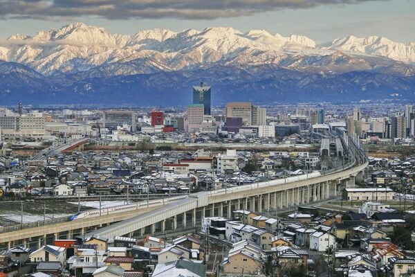 立山連峰をバックに走行する北陸新幹線の車両（富山市）