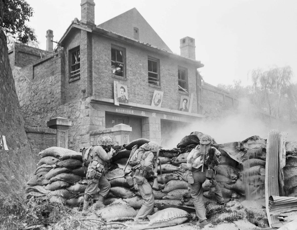 バリケードで身を守りながら平壌の市街戦を戦う米海兵隊。奥の建物にはソ連の指導者スターリンと北朝鮮の指導者金日成の肖像画が掲げられている/Bettmann Archive/Getty Images