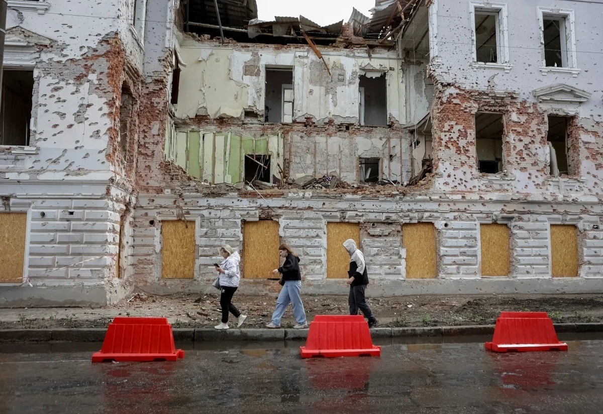 ロシア軍のミサイルによって破損した建物の前を歩く住民＝１３日、ウクライナ・スーミ州/Sofiia Gatilova/Reuters