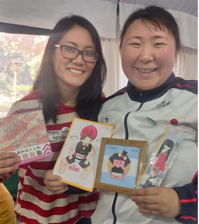 左は日系折り紙研究会野原ミミさん、右は今日和さん。真ん中にアルゼンチン国旗を背にした相撲折り紙。娘さんからの絵なども贈られた