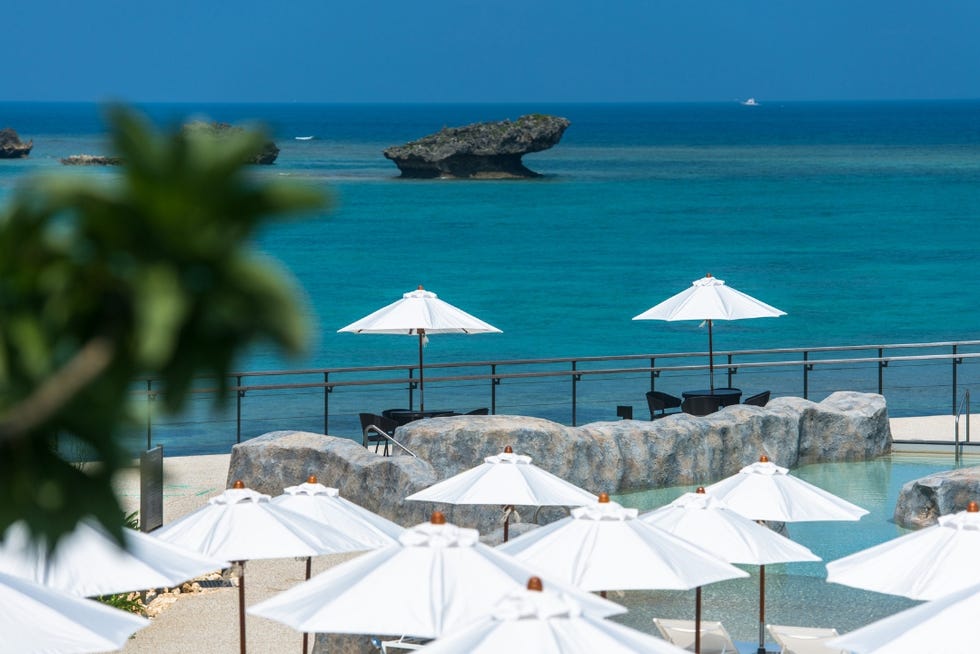 tropical seaside setting with umbrellas and rock formation