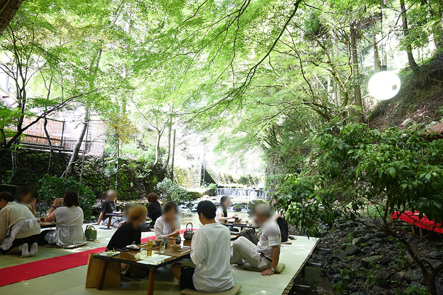 青紅葉のもと、貴船川の川床で多くの人が会席料理を味わう「鳥居茶屋 真々庵」