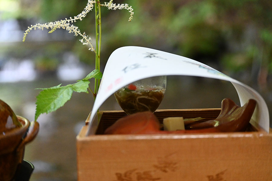 ネジバナなど季節の草花が添えられた重ね箱には、鴨ロース、海老の酒盗煮、鰻の八幡巻き、鶏肝の松風入り
