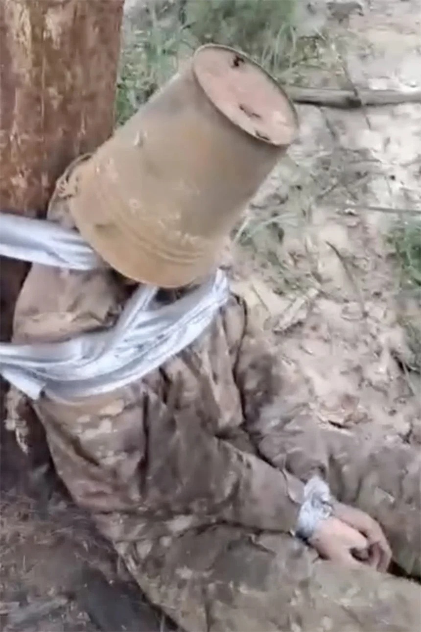 木に縛り付けられ、錆びたバケツを頭からかぶせられた男性/Telegram