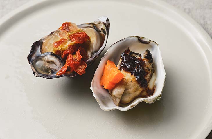 同じ食材への異なるアプローチが興味を引く一皿。松石シェフ（右）は豆鼓をあわせた中華風、寺田シェフ（左）は低温調理で生牡蠣のような味わいを演出