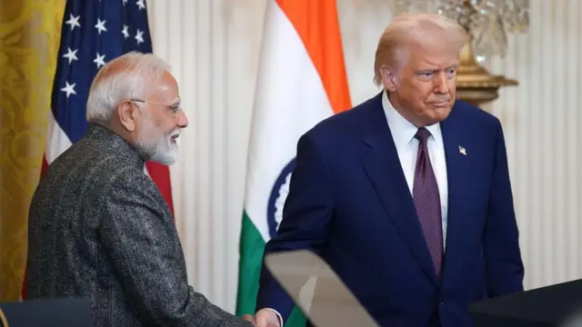 2月、ホワイトハウスでの記者会見でドナルド・トランプ大統領と握手するインドのナレンドラ・モディ首相。2人の背後にはインドとアメリカの国旗。モディは横顔で、トランプは前を向いている