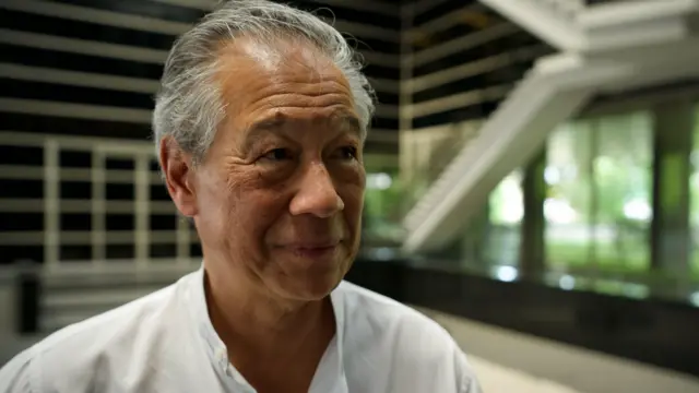 白髪交じりで白いシャツを着たハン氏が、微笑みながらBBCの取材を受けている