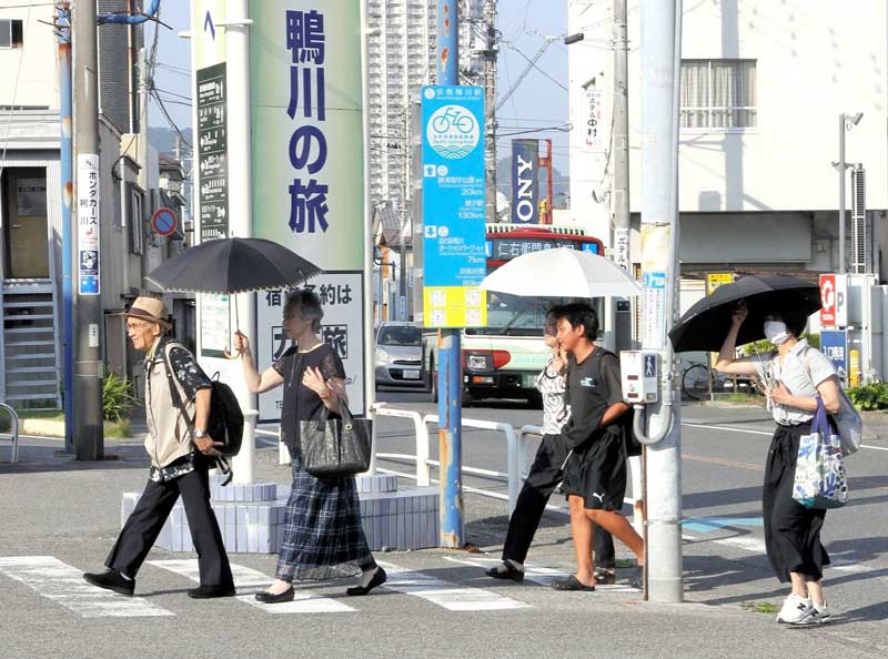 酷暑の中、日傘を差して歩く人たち＝６日午後、鴨川市（画像の一部を加工しています）