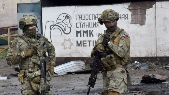 迷彩服を着てヘルメットをかぶり、機関銃を持ったロシア兵が2人立っている