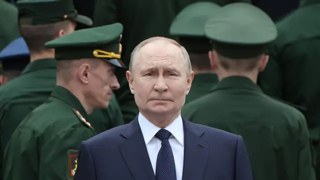 濃い緑色の軍服を着た軍人たちに囲まれたロシアのウラジーミル・プーチン大統領