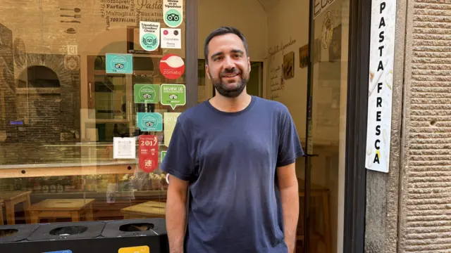 レストランの前に立つ男性。「Pasta Fresca（生パスタ）」と書かれた看板が出ている。