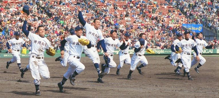 春夏通じて県勢初の甲子園優勝を果たし、アルプススタンドに向かって駆け出す沖縄尚学ナイン=1999年4月4日、甲子園球場(伊禮健撮影)