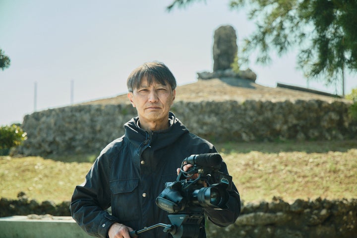 魂魄之塔の前に立つ、映画『摩文仁 mabuni』監督の新田義貴さん