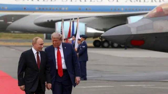 ダークスーツを着たロシアのプーチン大統領とアメリカのトランプ大統領が、アラスカ州の米軍基地の滑走路を並んで歩いている
