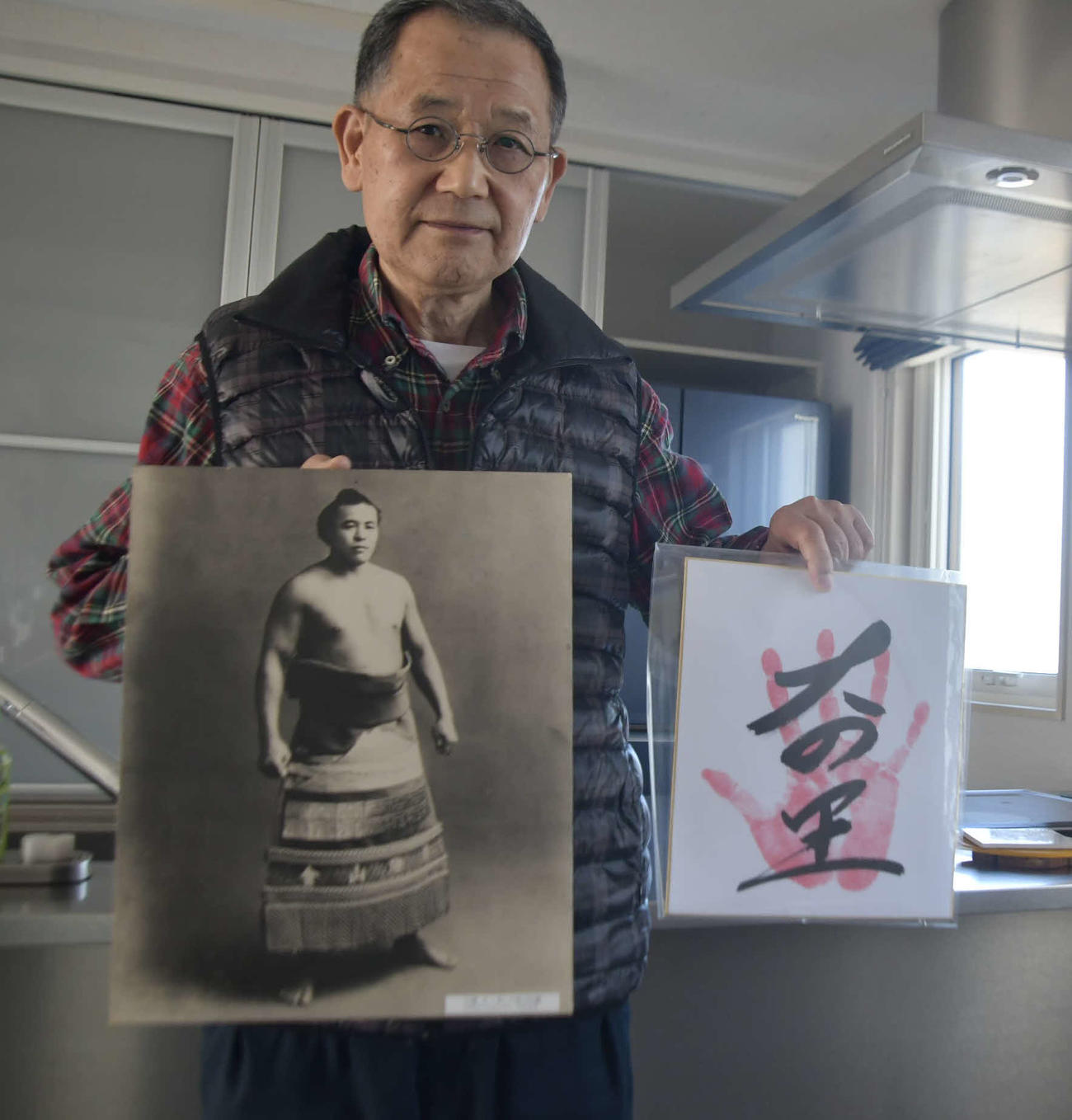 初代大ノ里の写真と2代目大の里の手形を持つ、初代大ノ里の一族の天内（あまない）司さん