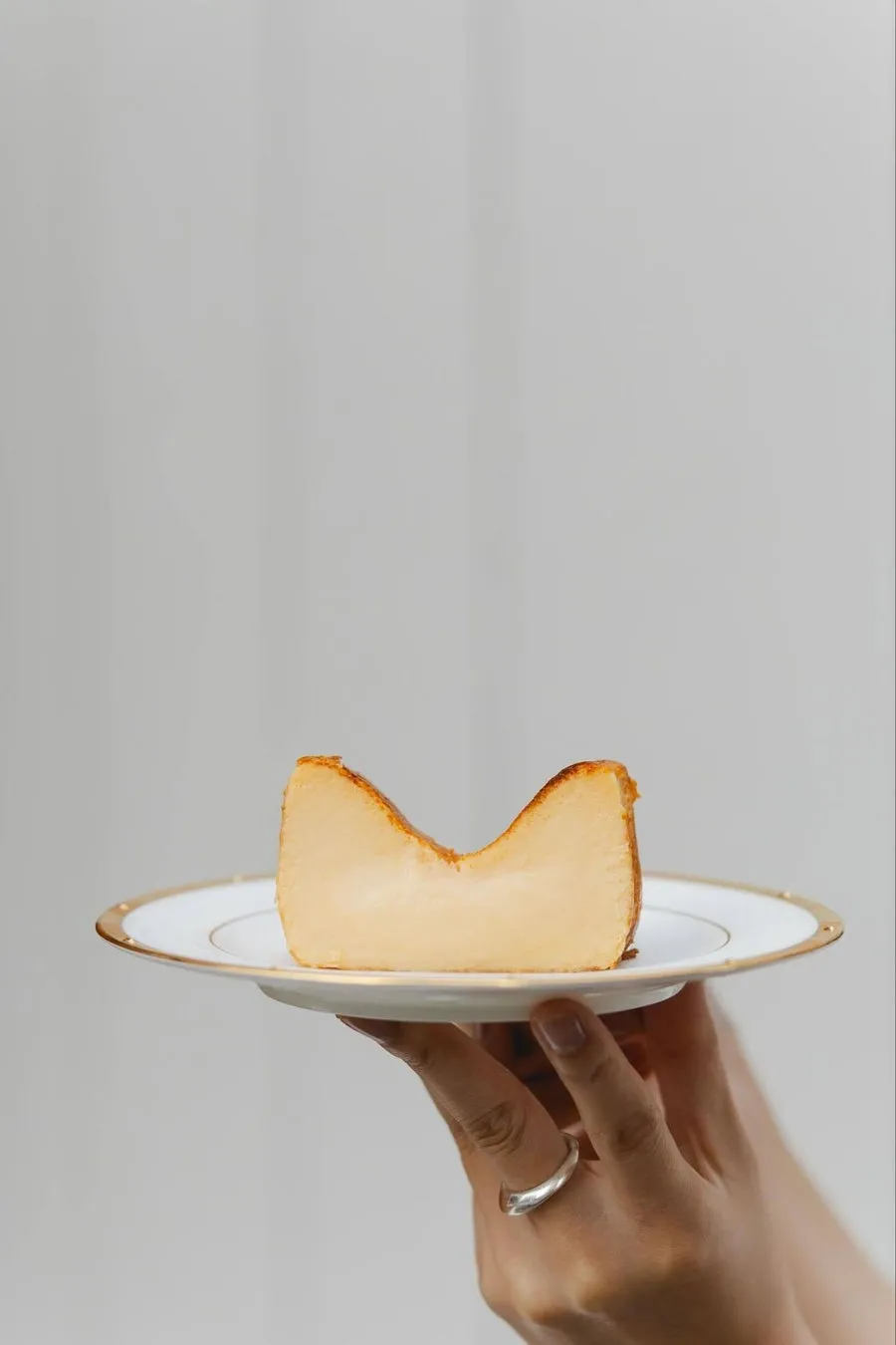 手で持たれたバスクチーズケーキのクローズアップ写真。