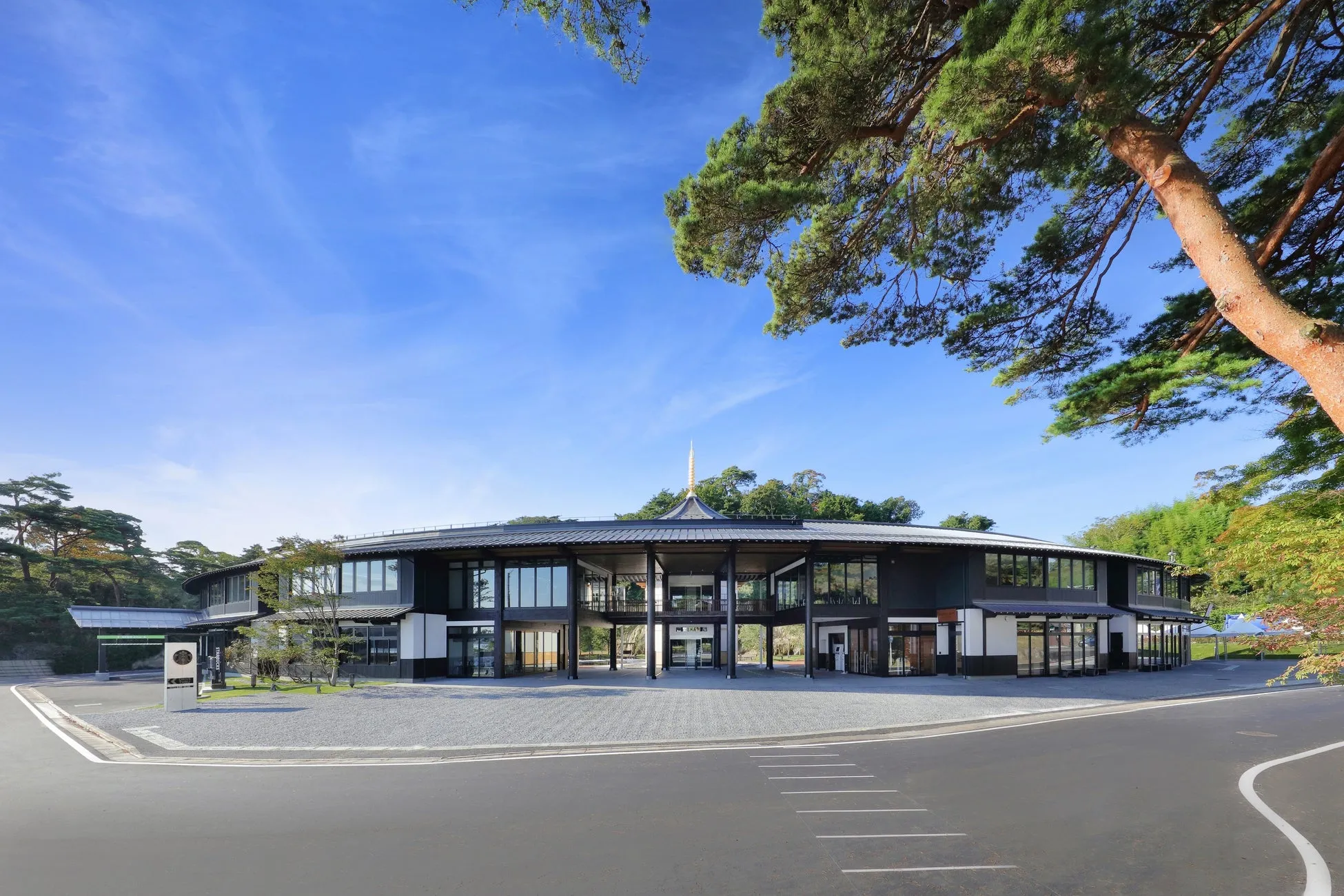 青空の下、円形をした美しい建物。建物の周りには緑豊かな木々が立ち並び、開放的な雰囲気。建物の入り口にはSTARBUCKSの看板が見える。