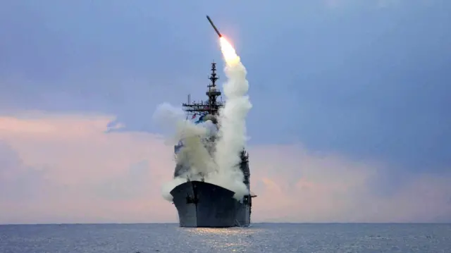 海に浮かぶ巡洋艦の甲板から、ミサイルが上方向に発射されている。ミサイルからは白い煙があがり、甲板に立ち込めている