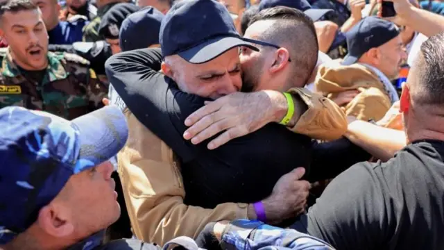 イスラエルから解放された男性が、家族と抱き合っている。周囲には多数の人がひしめいている